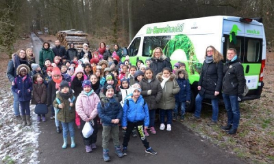 Das Liz-Mobil mit einer großen Gruppe Kinder und 7 Erwachsenen stehen auf einem Waldweg im Arnsberger Wald.