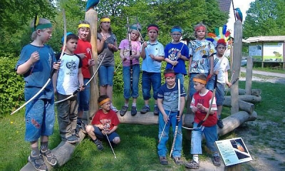 Eine Gruppe Kinder verkleidet mit Pfeil und Bogen nehmen an der Liz-Indianerwerkstatt teil.