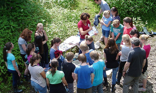 Eine Gruppe Schüler*innen erhalten Instruktionen für ein Waldtour
